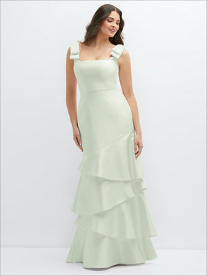 Light green satin maxi dress with bow-shoulder detail and asymmetrical tiered skirt.