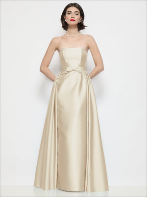 Champagne strapless satin column dress with waist bow detail and full gathered skirt