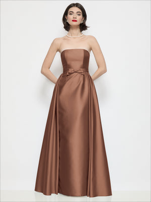 Cognac brown satin strapless column dress with bow at waist and overskirt
