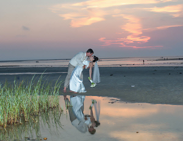 bride and groom kiss at sunset